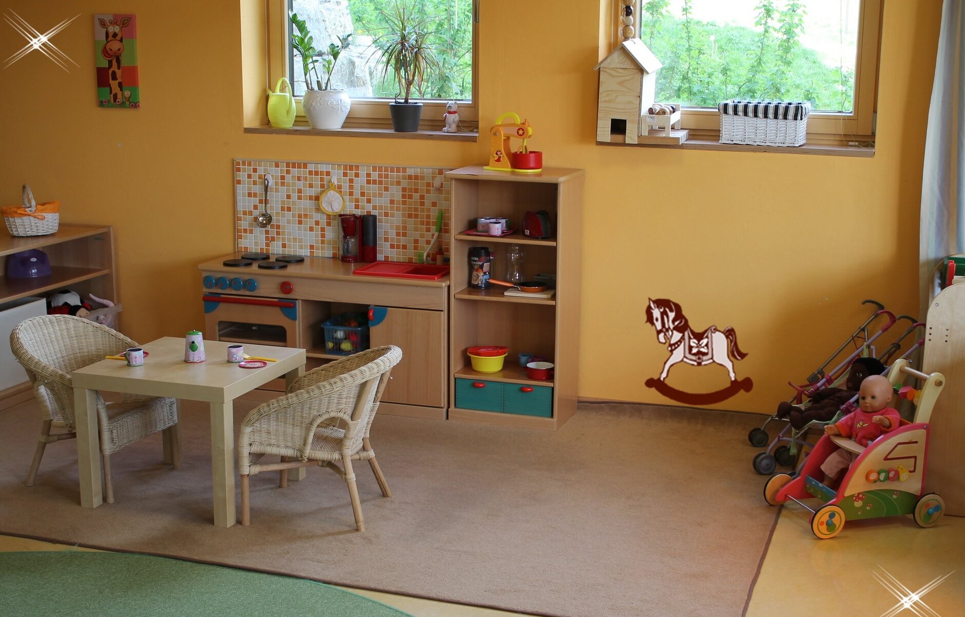 Spieleecke mit einem Kindertisch und zwei Kinderstühlen. Außerdem ist ein Puppenwagen zu sehen.